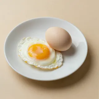 Huevo frito y huevo entero en un plato blanco